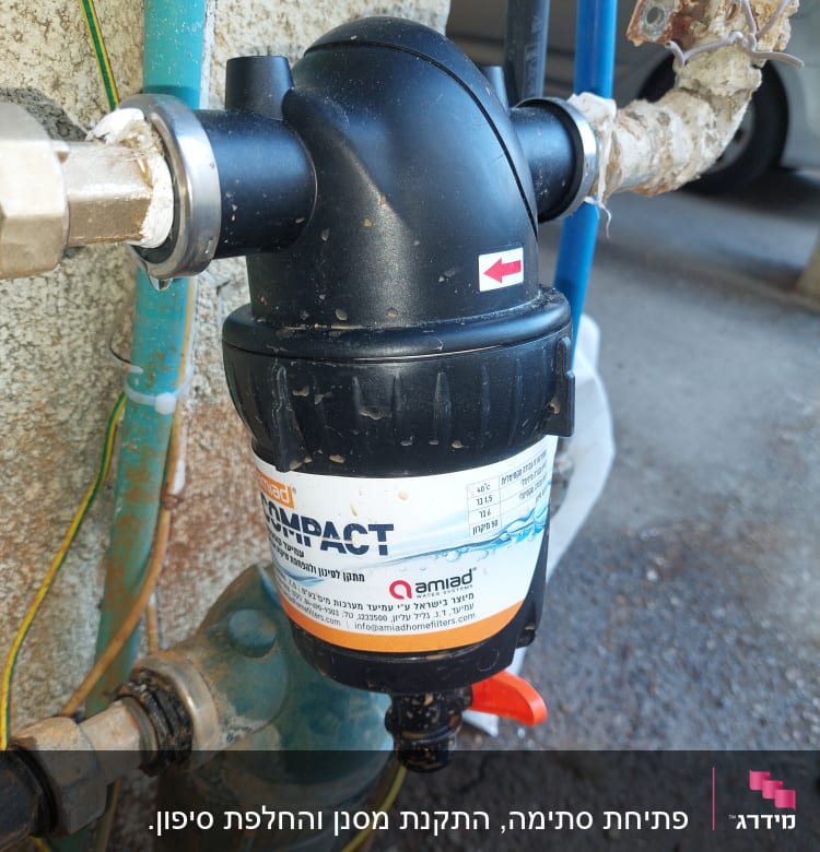 מסנן מים שחור מחובר לצינורות עם ברז אדום